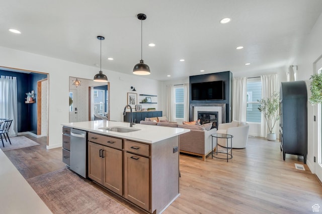 kitchen featuring a sink, light countertops, light wood-type flooring, an island with sink, and recessed lighting