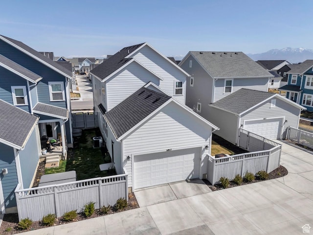 view of front facade featuring driveway, a residential view, and fence private yard