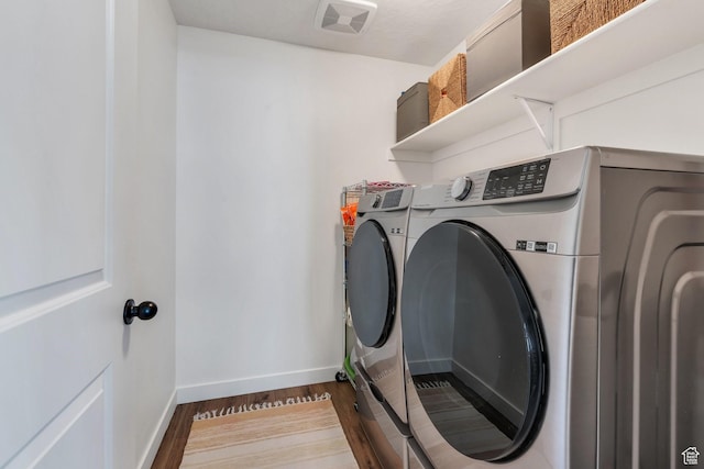 laundry room featuring visible vents, baseboards, laundry area, wood finished floors, and washer and clothes dryer