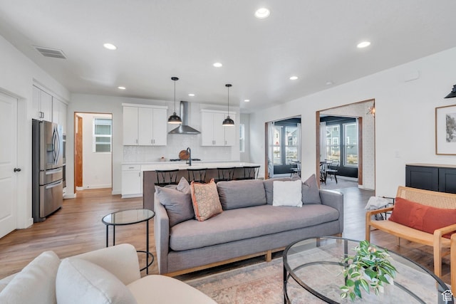 living room with light wood finished floors, visible vents, and recessed lighting
