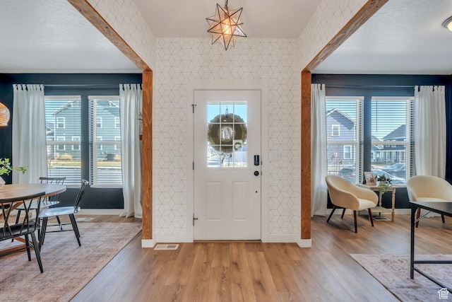 entryway featuring baseboards, light wood-type flooring, an accent wall, and wallpapered walls