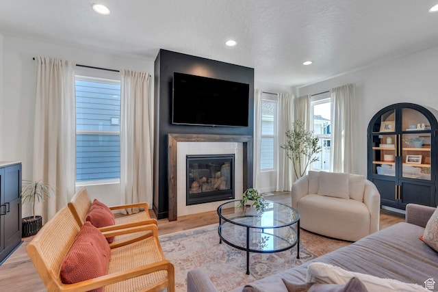 living room with light wood-style flooring, a glass covered fireplace, and recessed lighting