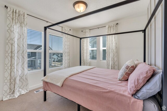 bedroom with visible vents, multiple windows, baseboards, and carpet floors
