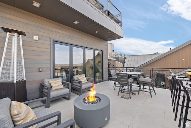 view of patio featuring a fire pit, a balcony, and outdoor dining area