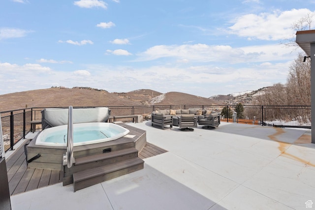 exterior space featuring a covered hot tub, a mountain view, and outdoor lounge area