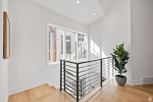 interior space with visible vents, an upstairs landing, wood finished floors, and lofted ceiling