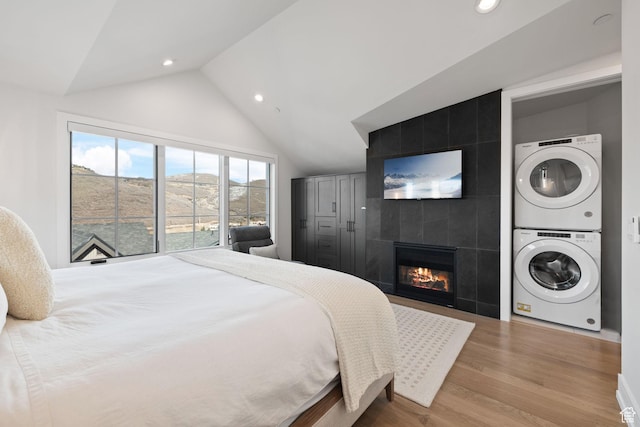bedroom featuring recessed lighting, stacked washer and dryer, wood finished floors, and lofted ceiling