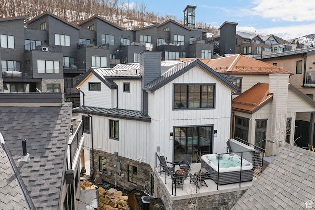 rear view of house with a hot tub, a patio area, metal roof, board and batten siding, and a standing seam roof