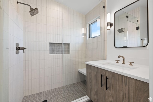 bathroom with a tile shower and vanity