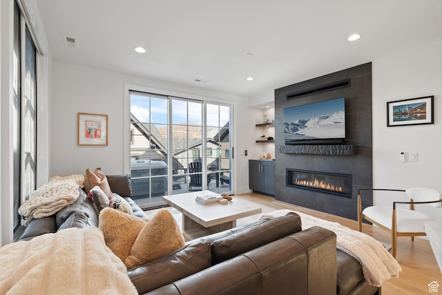 living room with recessed lighting, a fireplace, and light wood-type flooring