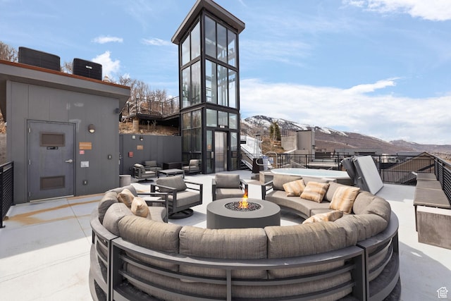 view of patio with central air condition unit, a mountain view, and an outdoor living space with a fire pit