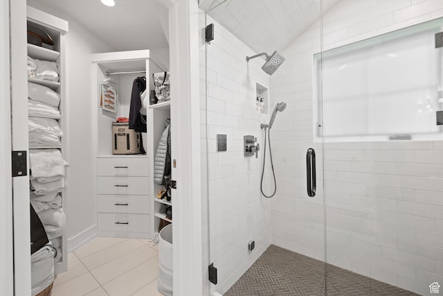 bathroom featuring a shower stall, a walk in closet, and tile patterned flooring