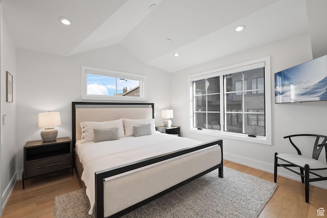bedroom with light wood finished floors, baseboards, and lofted ceiling