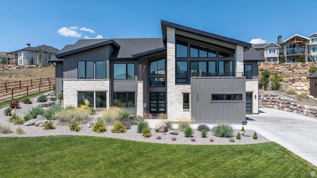 back of property with stone siding, board and batten siding, fence, and a lawn