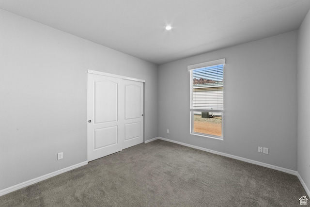 unfurnished bedroom with carpet flooring, baseboards, and a closet