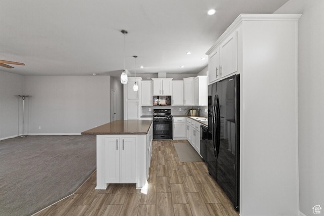 kitchen with white cabinetry, open floor plan, light wood finished floors, and black appliances