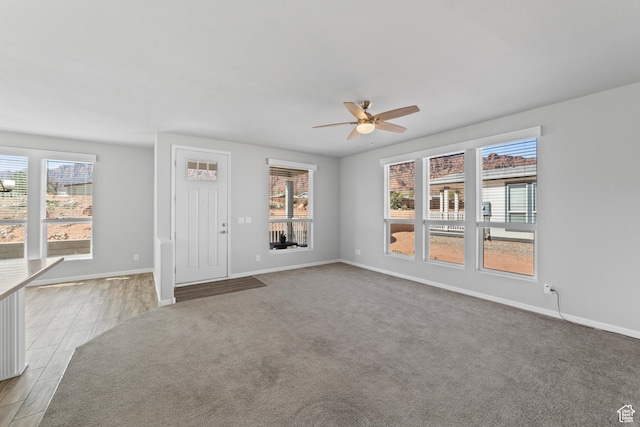unfurnished living room featuring light wood-style floors, baseboards, a ceiling fan, and a wealth of natural light