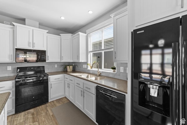 kitchen with white cabinets, a sink, black appliances, and tasteful backsplash