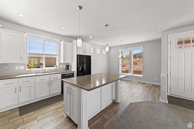 kitchen with white cabinetry, a sink, wood finished floors, and black appliances