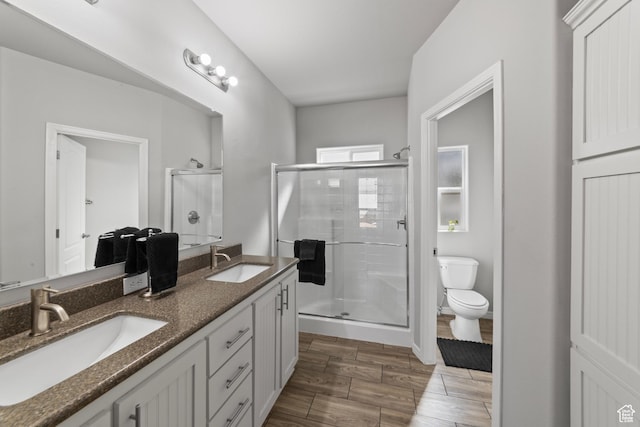 full bath with a sink, a shower stall, toilet, and double vanity
