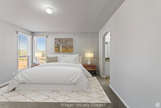 carpeted bedroom featuring arched walkways and baseboards