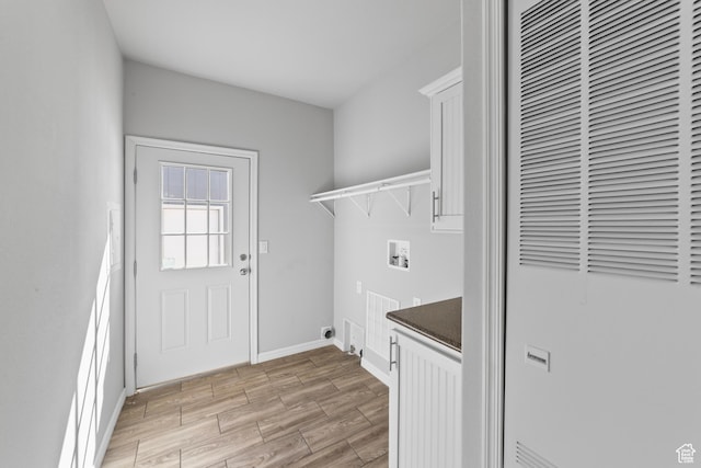 laundry room with cabinet space, hookup for a washing machine, a heating unit, baseboards, and light wood-type flooring