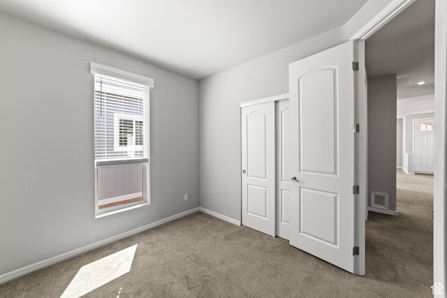 unfurnished bedroom with carpet floors, baseboards, multiple windows, and a closet