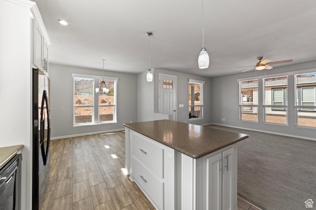 kitchen featuring a center island, baseboards, ceiling fan with notable chandelier, dishwashing machine, and white cabinetry