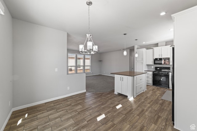 kitchen with dark wood-style flooring, baseboards, an inviting chandelier, and black appliances