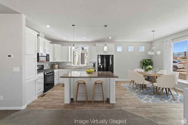 kitchen with a kitchen island, backsplash, black appliances, recessed lighting, and white cabinetry