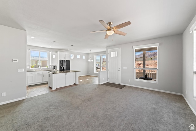 unfurnished living room with baseboards, a ceiling fan, and plenty of natural light