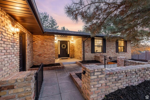 exterior entry at dusk featuring brick siding