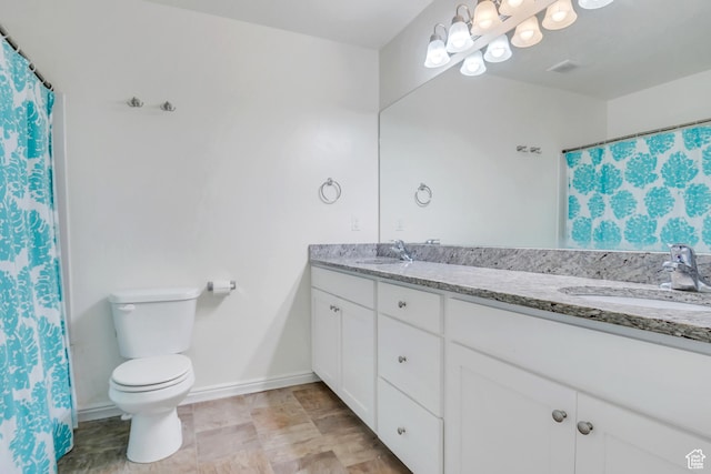 full bath featuring a sink, toilet, double vanity, and baseboards