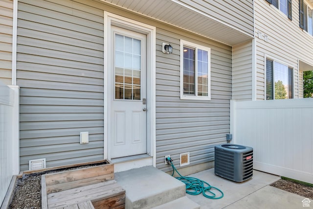 entrance to property featuring central AC and fence