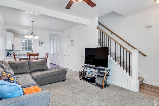 carpeted living room featuring stairs, ceiling fan with notable chandelier, and ornamental molding