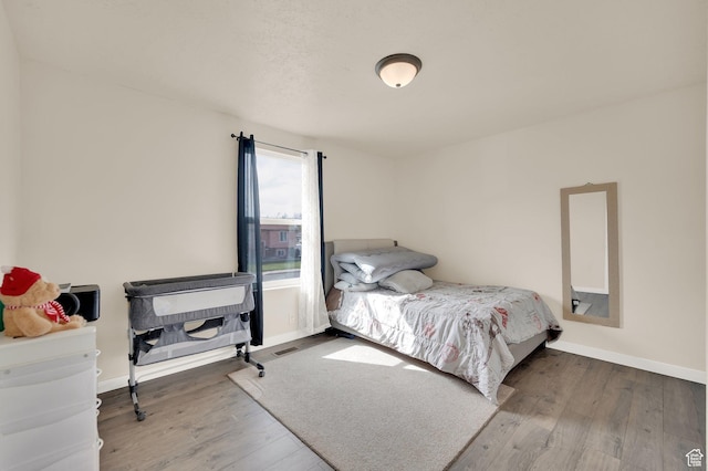 bedroom with visible vents, baseboards, and wood finished floors
