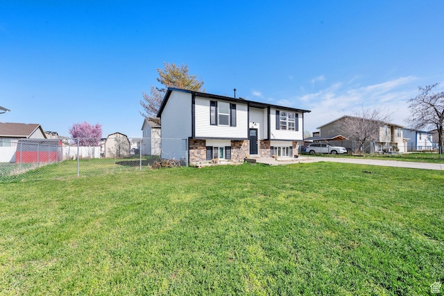 view of front of house featuring stone siding, fence, and a front lawn