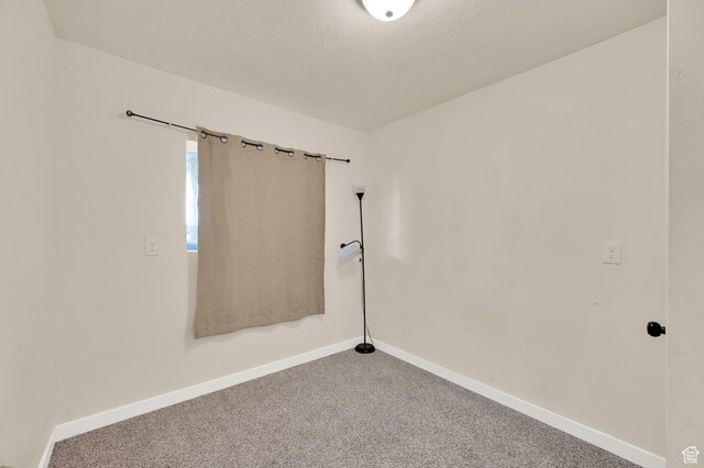 carpeted empty room featuring baseboards