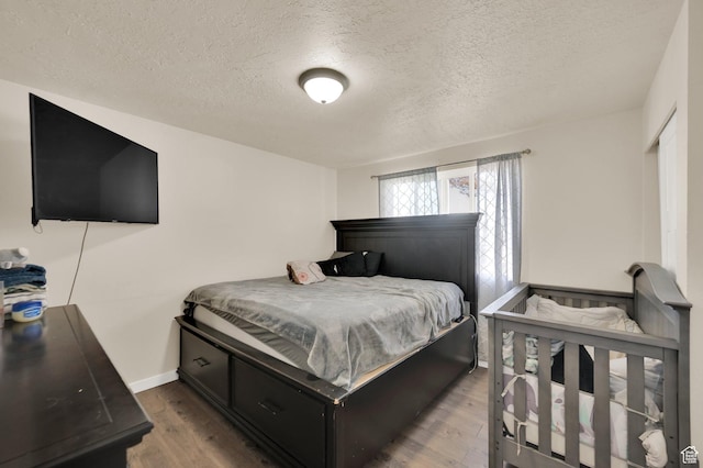 bedroom with baseboards, wood finished floors, and a textured ceiling