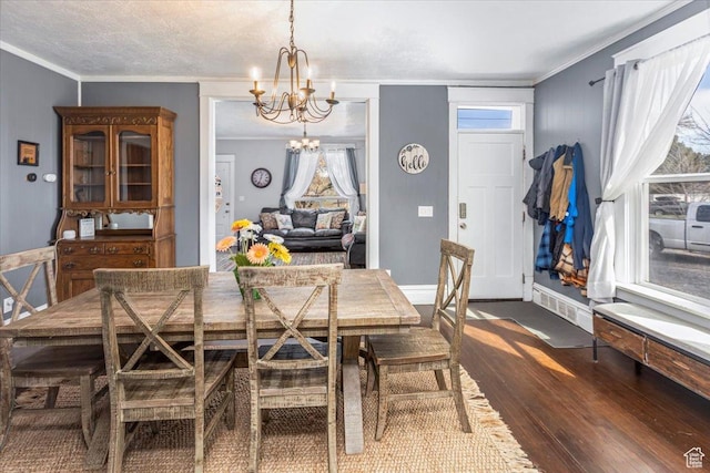 dining space with ornamental molding, an inviting chandelier, and dark wood finished floors