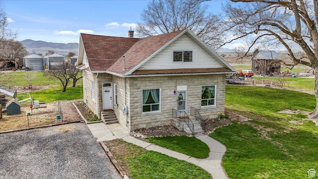 bungalow featuring roof with shingles, a mountain view, and a front yard