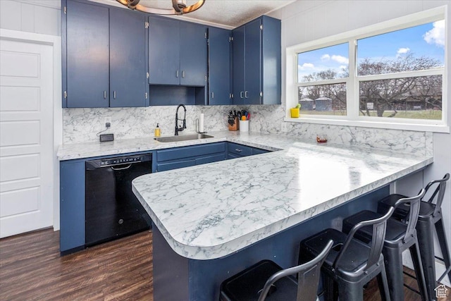 kitchen featuring dark wood-style floors, blue cabinetry, black dishwasher, decorative backsplash, and a sink
