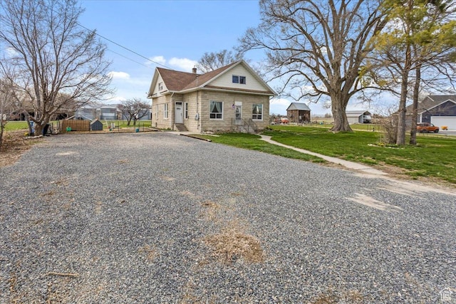 view of front of house featuring a chimney, fence, gravel driveway, and a front lawn