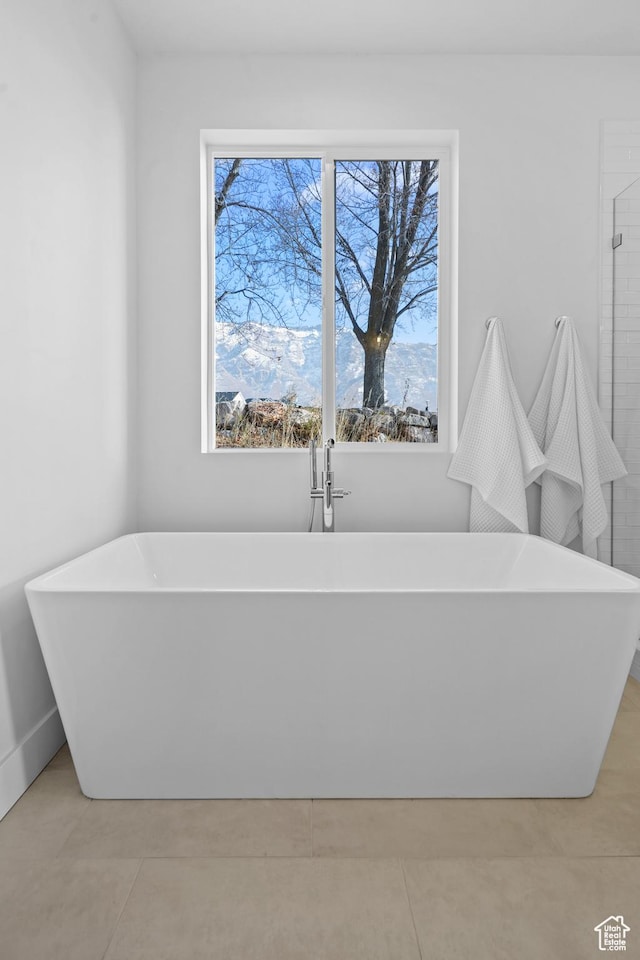 full bathroom featuring tile patterned floors, plenty of natural light, and a freestanding bath