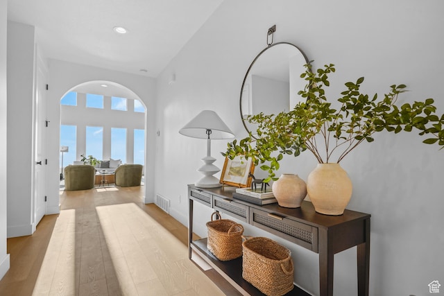 hall with arched walkways, wood finished floors, visible vents, and recessed lighting