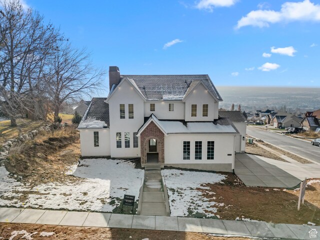 view of front of home featuring brick siding, stucco siding, and a chimney