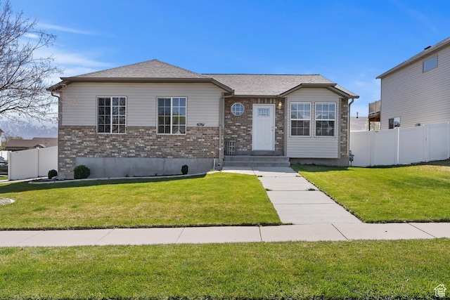 view of front facade with a front yard, brick siding, and fence