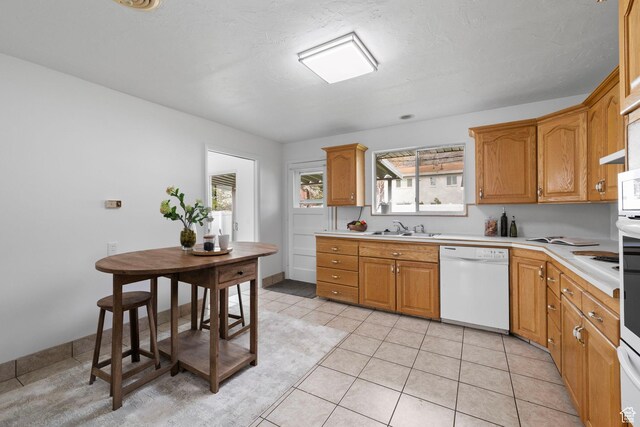 3481 S 3530 E, Salt Lake City, UT 84109 - kitchen with light tile patterned floors, light countertops, brown cabinetry, white dishwasher, and a sink
