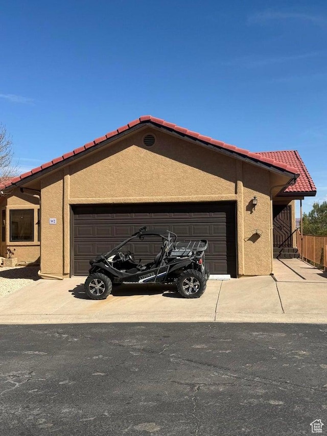 view of front of property featuring concrete driveway, stucco siding, an attached garage, and a tile roof