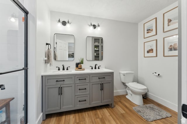 bathroom featuring a sink, toilet, a stall shower, and wood finished floors